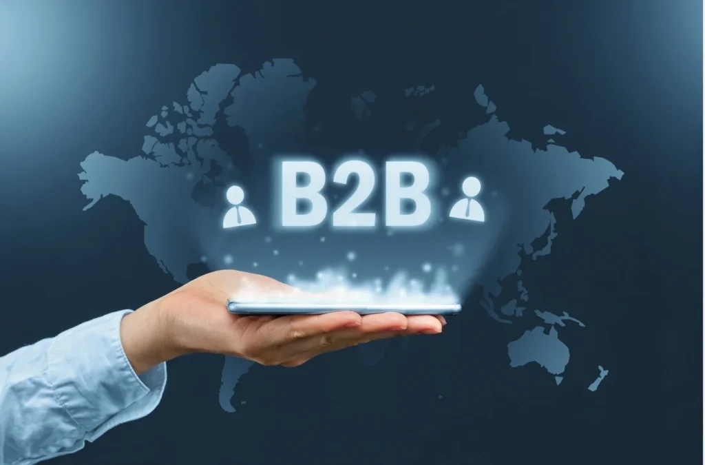 Hand holding a digital tablet with glowing B2B icons over a world map background, symbolizing global business connectivity.